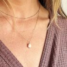 pearl pendant on gold chain worn with a gold satellite chain choker