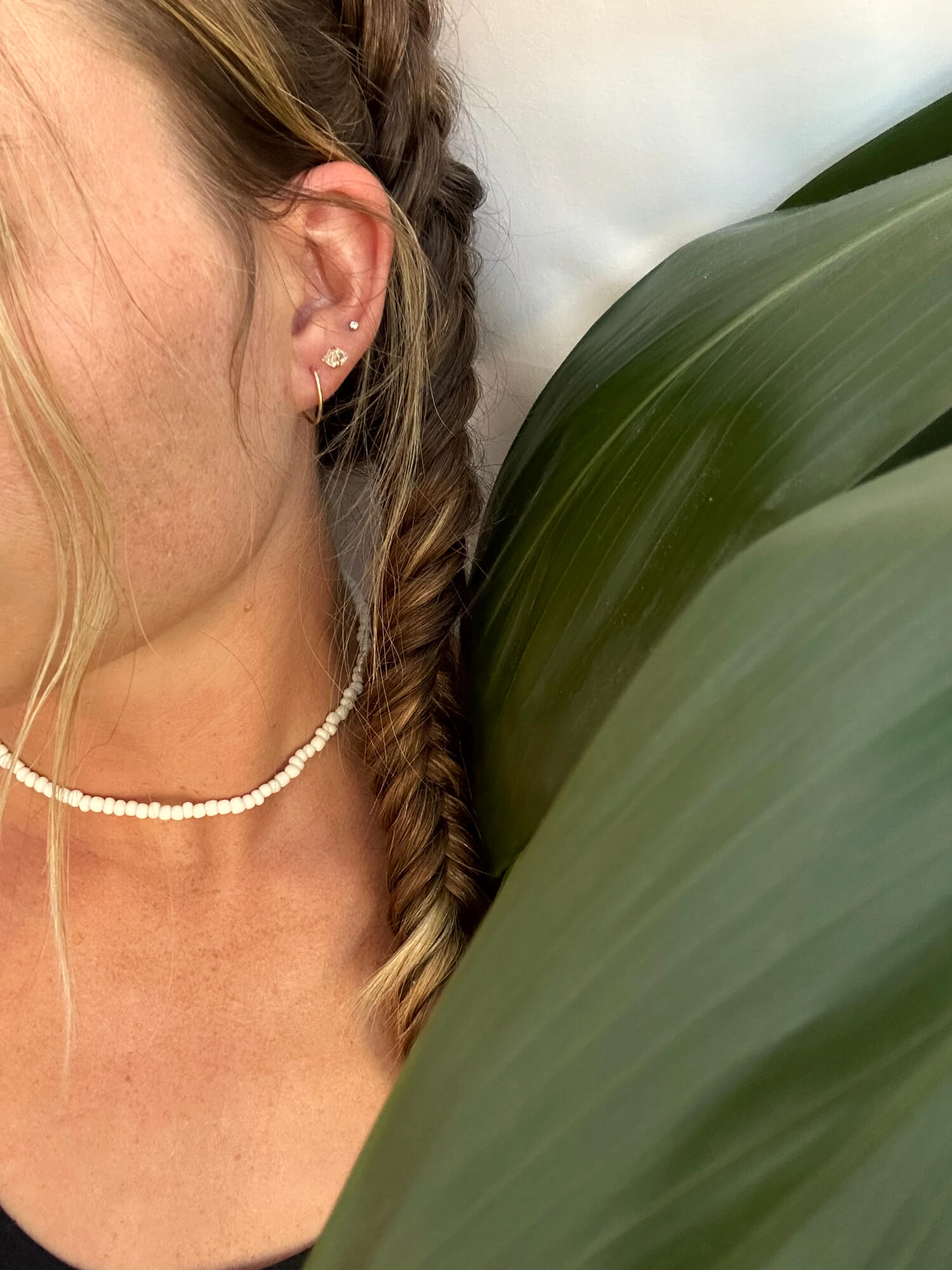 small gold hoops, diamond earrings, white beaded choker on a girl with fishtail braids