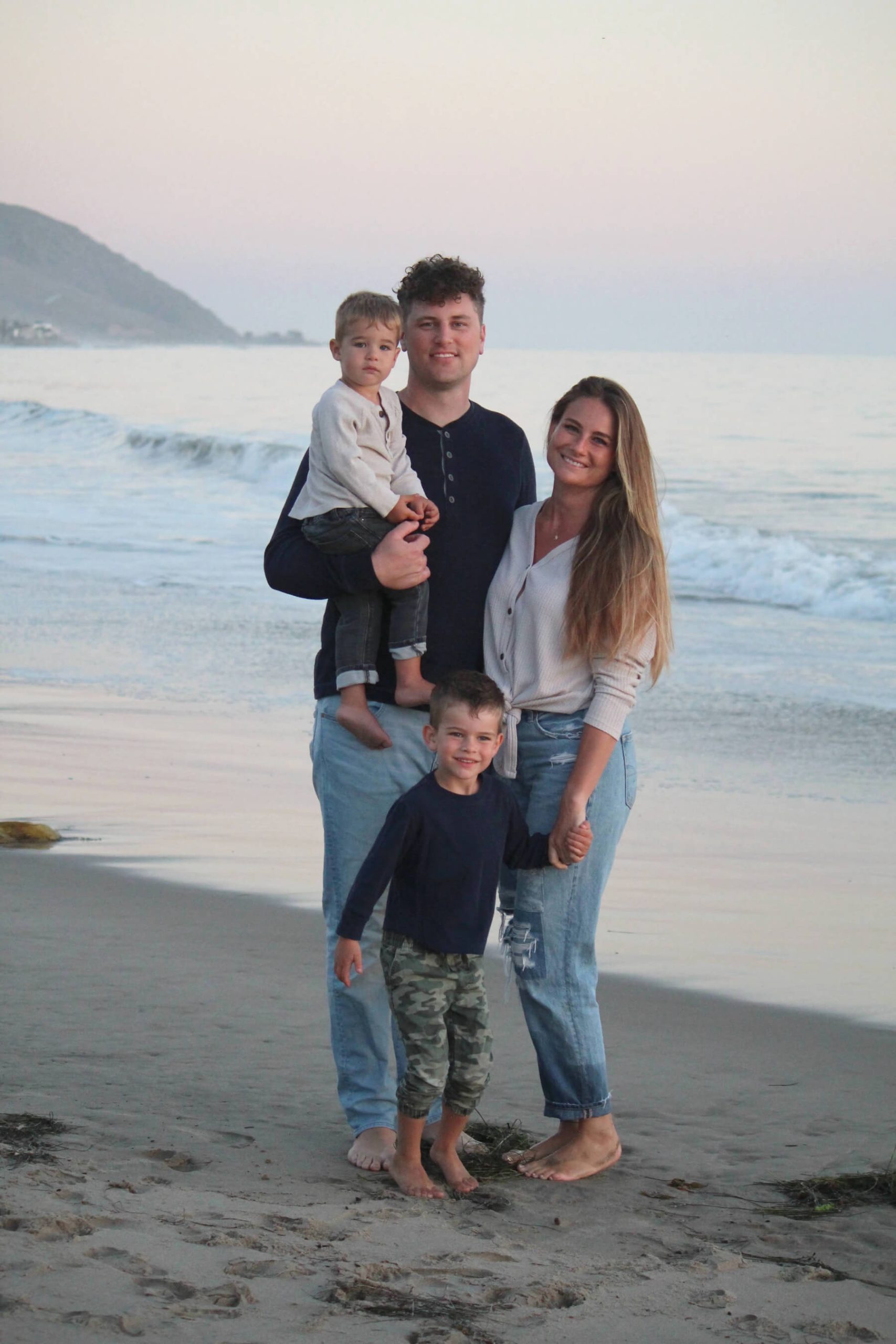 a family of a mother, father and two boys on a beach