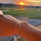 Shows paperclip chain, beaded bracelet, and mini link chain bracelet stack with a sunset
